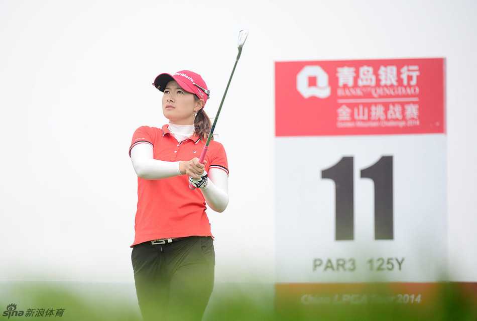 张素荣站在开阔的球道上向远方眺望，仿佛在思考接下来的战术，风吹动她的衣角，画面宁静而富有张力。