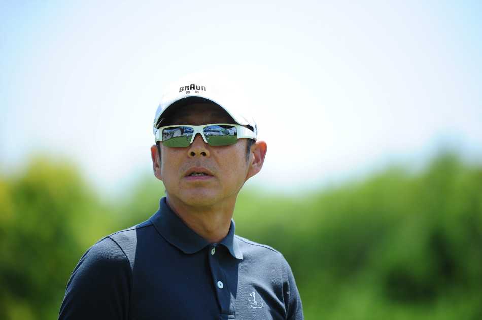 陈道明阔步行走于开阔的球道上，步伐稳健，目光悠远，仿佛一位漫步于自己精神领地的思考者