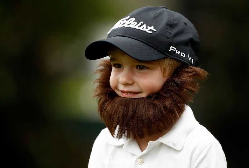 一位身穿红色雨衣的小球迷，在绵绵细雨中手扶围栏，全神贯注地望向球员通道，眼中充满了期待。