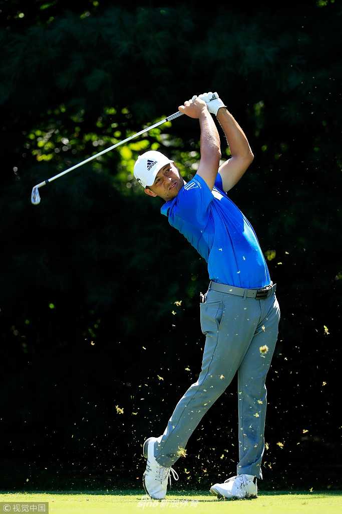 里奇·福勒在果岭边进行精准的切杆，他身穿标志性的橙色服装，神情专注，动作优雅，小球被轻轻挑起飞向旗杆。