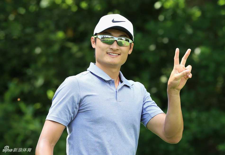 李昊桐与球童在练习果岭边并肩而立，低头认真探讨推杆线路，神情严肃而专注