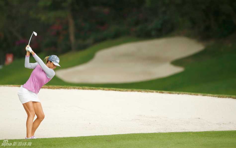 迈向果岭。球员自信从容地走在开阔的球道上，背景是蓝天与绿树，步伐坚定，尽显征战赛场的王者风范。