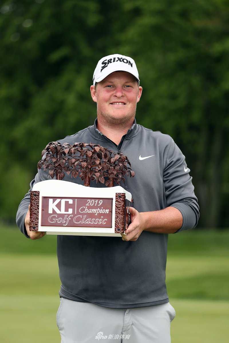 吉勒曼母亲手持粉红色果岭旗，笑容灿烂，眼中满是对儿子的无限自豪与慈爱。