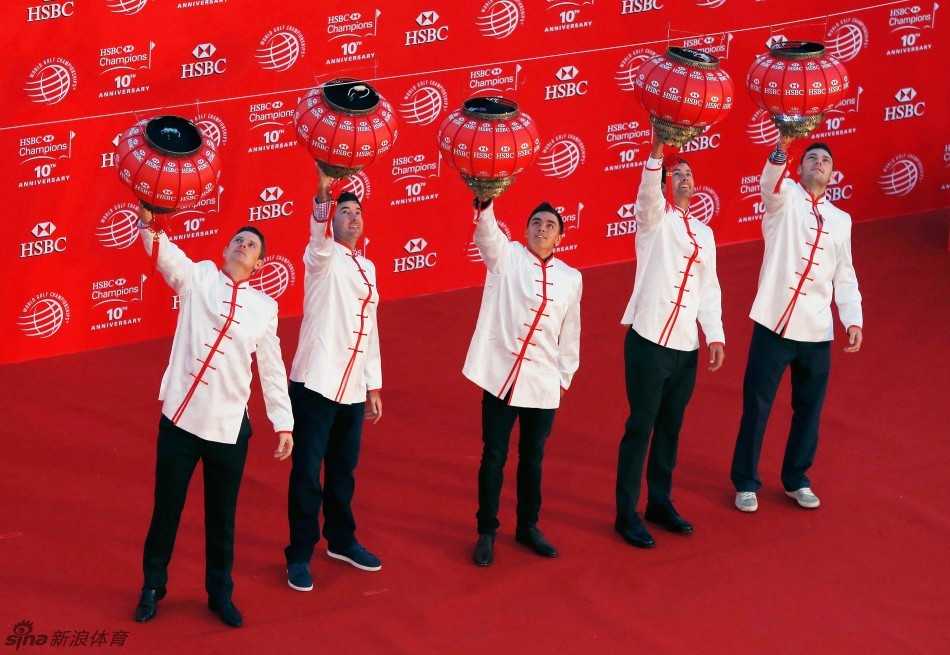 里奇·福勒面带微笑，正站在一个特制的垫脚台上，伸手准备将手中的大红灯笼挂起，背景是华丽的酒店内部装饰。