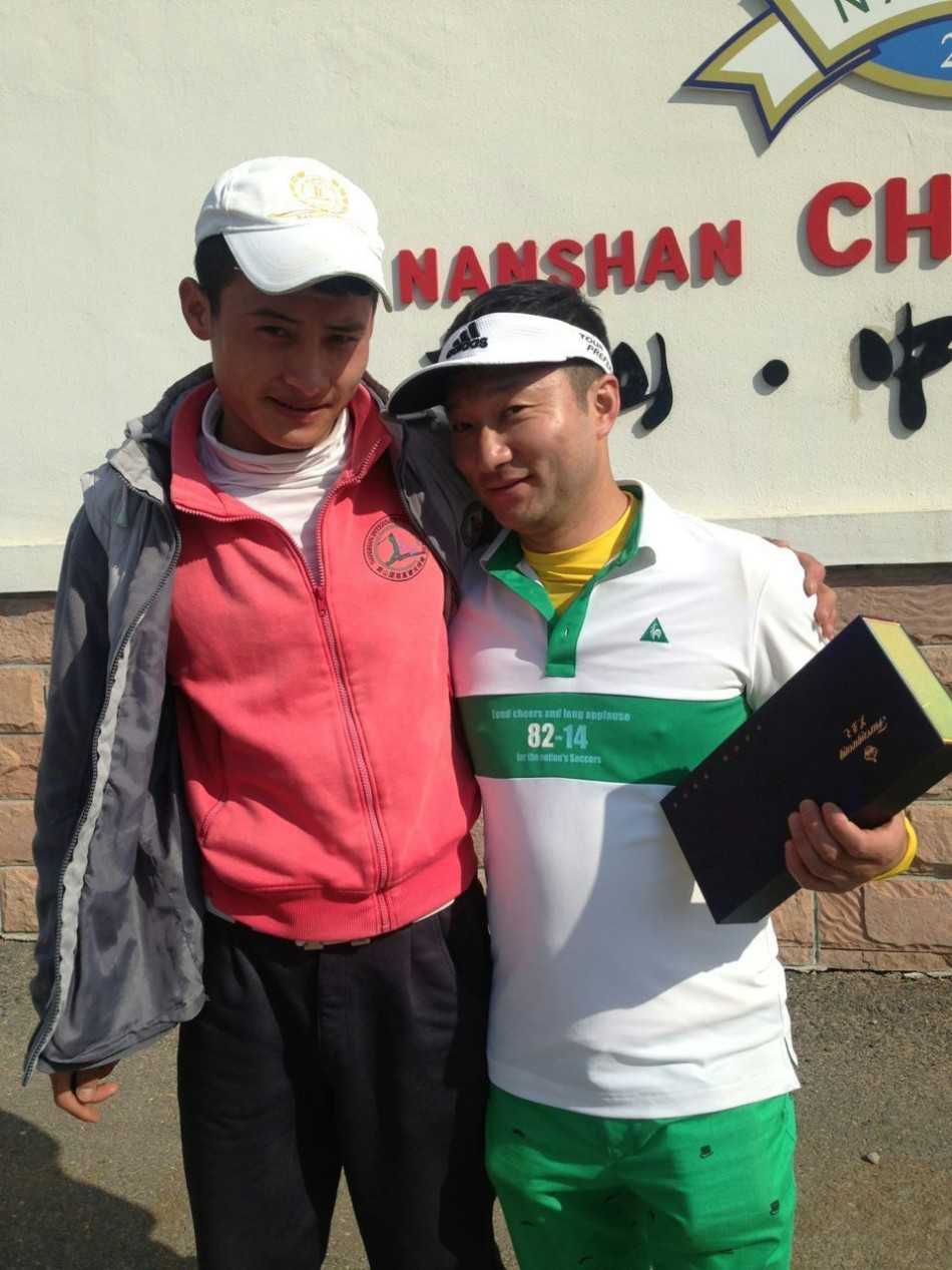 活动现场全景，雅致的接待台与主题展示区融入球场会所环境，工作人员正为来宾提供细致周到的服务。