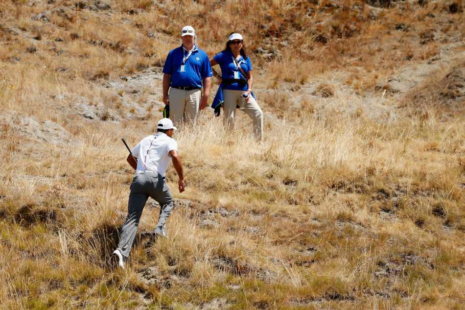 伍兹在山坡上快速奔跑，追踪刚刚击出小球的飞行轨迹，其矫健的身影与绿茵场地构成一幅动感画面。